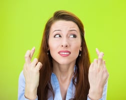 Closeup portrait of sad, worried, concerned woman, student, mother crossing her fingers hoping, asking for best, isolated green background. Human face expressions, emotions, feeling, attitude reaction